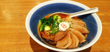 Sebzeli ramen şehriyesi, dilimlenmiş taze soğan ve mavili ördek çorbası ve fotokopi alanı. Asya 'daki ünlü Japon yemekleri kahverengi ahşap arka planda..