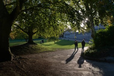 Sheffield, Birleşik Krallık, 21 Ekim 2021: Siluetli bir çift Sheffield botanik bahçelerinin ana girişi yakınlarındaki ikonik seraya doğru yürüyor