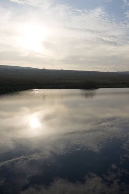 Mavi bulutlu gökyüzünün dikey görüntüsü Redmires üst rezervuarına yansıyor. Heather 'ın tepesiyle kaplı kırlık arazide güneşe bakıyorum. Kış mevsimi.
