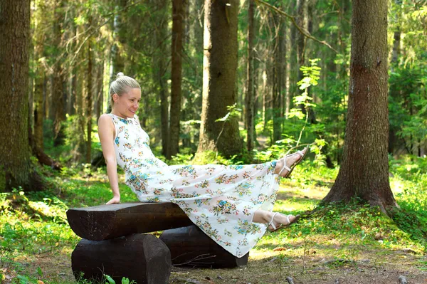 Beautiful girl in the woods on a wooden bench — Stock Photo, Image