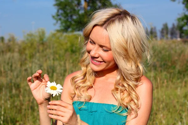 Menina em um vestido brilhante com flores nas mãos sobre o fundo da natureza — Fotografia de Stock