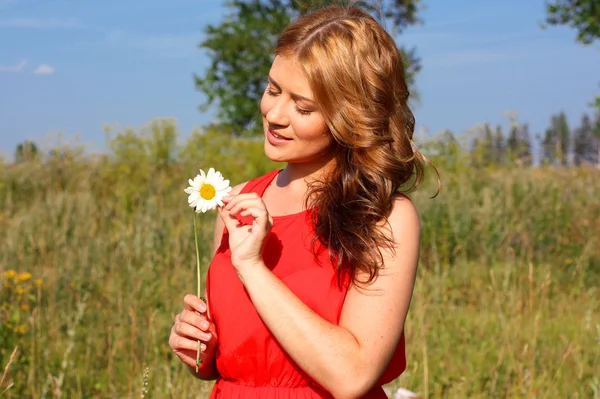 Girl in a bright dress with flowers in hands on nature background — Stock Photo, Image