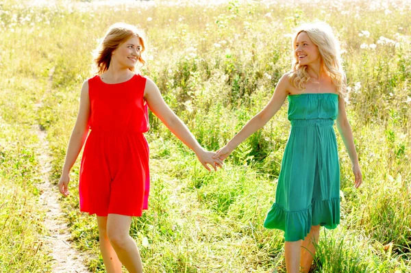Two girls in dresses walking in a field — Stock Photo, Image