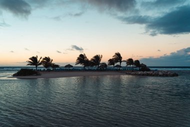 Gün batımından sonra küçük turistik bir ada, palmiyelerin altında boş plaj sandalyeleri, Jamaika