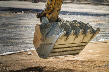 Yerin hemen üstündeki kazı kovası, inşaat işi. İnşaat alanının bulanık arkaplanı
