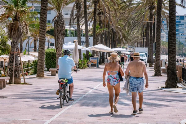 Bir çift yaşlı insan Marbella 'da deniz kıyısında yaya caddesinde yürüyor. Marbella, Malaga / İspanya - 21 Temmuz 2022