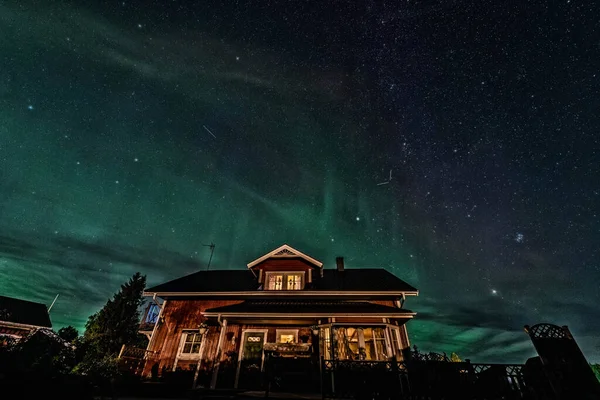 星の道とオーロラ スウェーデンの田舎の家 夜の風景の上に星の道と光オーロラのボアリスをキャプチャするための長い露出 — ストック写真