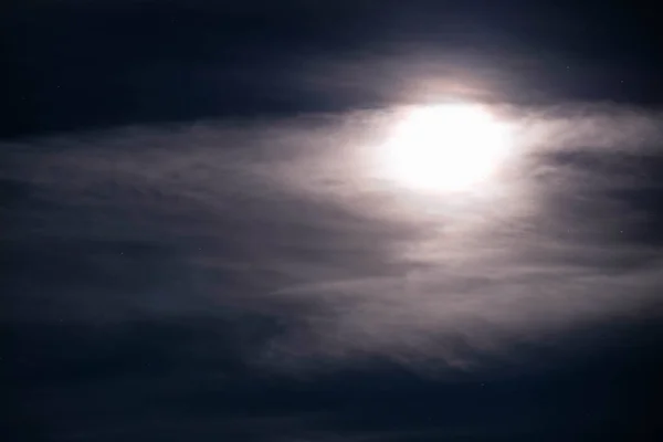 Shiny full Moon behind cloud on night starry sky