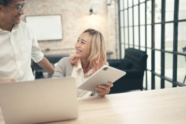 Ofiste arkadaşıyla tablet tutan mutlu çırak kadın.