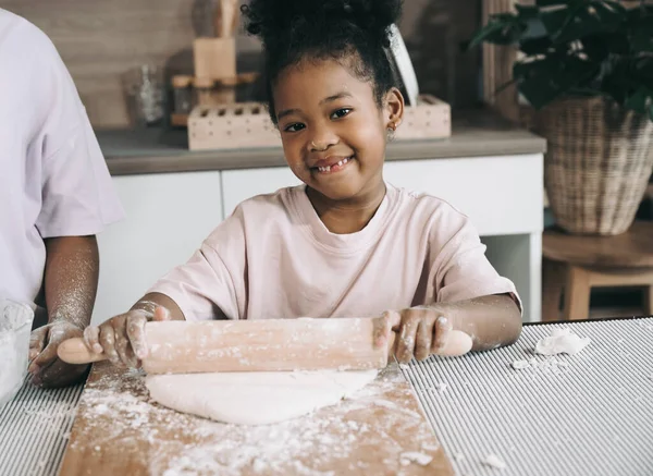 Mutfakta merdanesi olan siyah tenli mutlu çocuk.