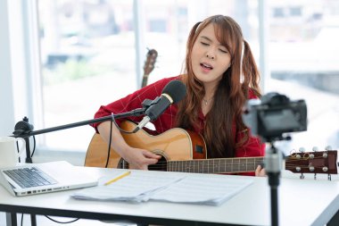 Gitar çalan Asyalı kadın video blogu kaydediyor