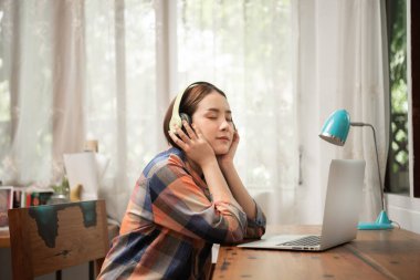 Evde kulaklıkla müzik dinleyen güzel bir kadın.