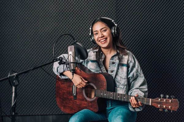 Müzik stüdyosunda gitar çalan güzel bir kadın.