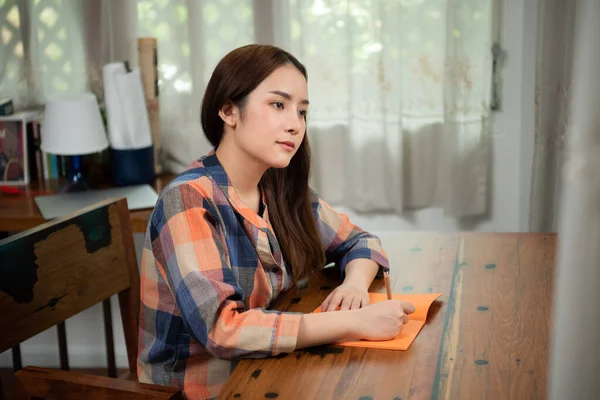 Rahatla güzel kadın oturma odasında defter yazıyor.