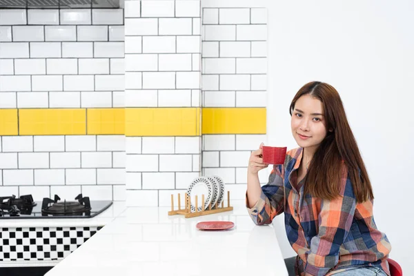 Sakin ol, Asyalı kadın mutfakta kahve içiyor.