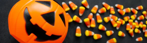 Banner Candy corn candies spilled out of the pumpkin basket. Traditional sweets on Halloween. Treat or trick.