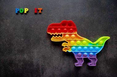 Oyuncak dinozor gökkuşağı renginde siyah arka planda çok renkli harfler ve harfler var. Boşluğu kopyala.