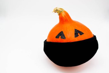 Cadılar Bayramı ve covid-19: beyaz arka planda siyah maskeli parlak turuncu bir balkabağı. Uzayı kopyala Boo!.