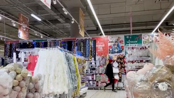モスクワ ロシア 2021年11月 ショッピングバスケットを持つ若い男性は ショッピングモールで販売されている赤 金のクリスマスの装飾の行を過ぎて歩く — ストック動画