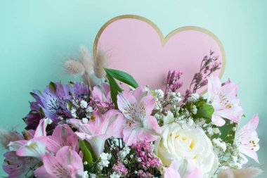 Zarif buket pembe zambaklar, beyaz güller, çingeneler. Turkuaz arka plan. Pembe Kalp, boşluğu kopyala.