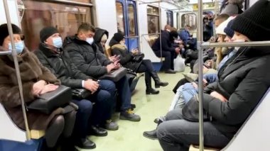Moskova, Rusya, Aralık 2021: Bir metro vagonunda koruyucu maskeli yolcular. Bir salgın sırasında şehrin kuralları.