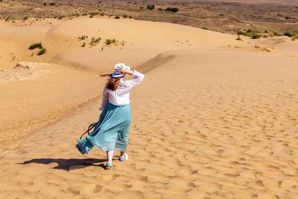 Widok z tyłu dziewczyny chodzącej po wydmach na pustyni z czystym niebem Obraz Stockowy
