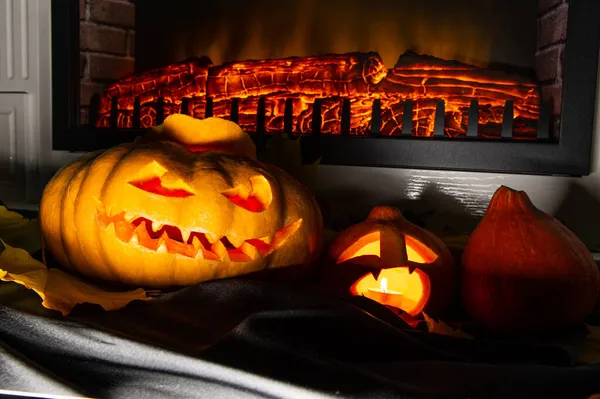 Dos calabazas de Halloween junto a la chimenea con un fuego en la oscuridad, enojado y asustado — Foto de Stock