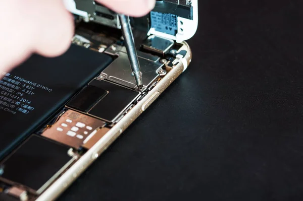 Primer plano con la reparación de un teléfono inteligente usado con un destornillador — Foto de Stock