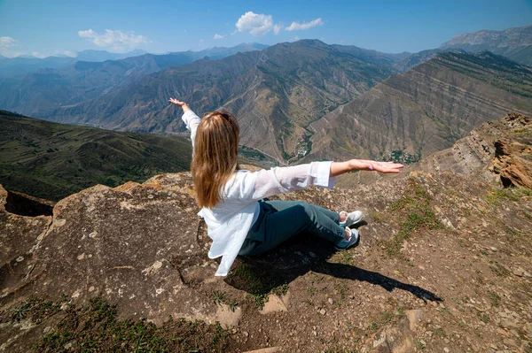 Een meisje zittend op een rots op een klif in canyon, Dagestan — Stockfoto