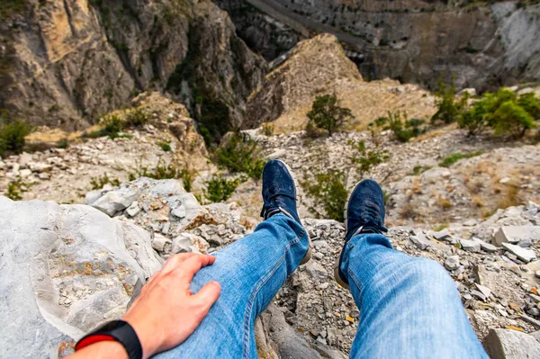 Vista de los pies de un viajero masculino en zapatillas de deporte en una colina disfrutando de la vista — Foto de Stock