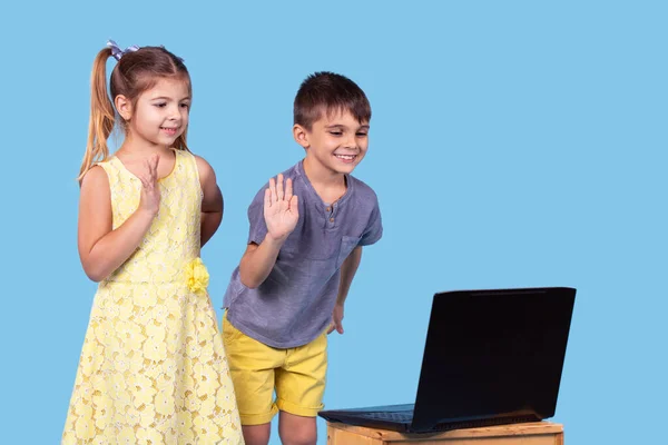 Χαμογελώντας λίγο καυκάσιος παιδιά έχουν βίντεο κλήση μακρινή τάξη με δάσκαλο χρησιμοποιώντας φορητό υπολογιστή χαιρετισμό μαζί της, κατ 'οίκον διδασκαλία έννοια. — Φωτογραφία Αρχείου