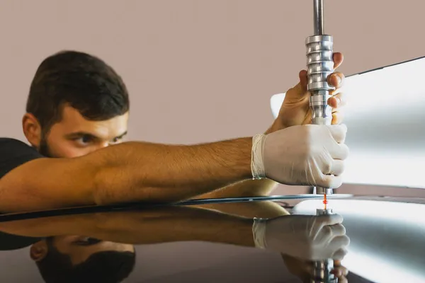 Koruyucu eldiven kullanan teknisyen, arabanın çatısında ve PDR Tahliye Kursu 'nda acısız çukur onarımına devam ediyor..