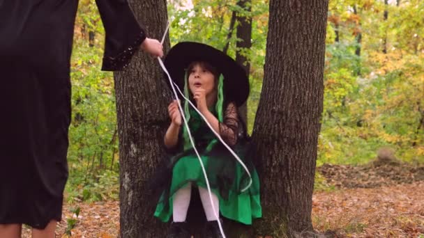 Nuori tyttö Halloween mekko järkyttynyt istuu kahden puun välissä ja saatuaan ilmapalloja nainen on erittäin onnellinen. — kuvapankkivideo