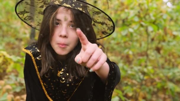 Primer plano de vídeo de una chica con traje para Halloween estar en el bosque apuntando a la araña en la malla y riendo. — Vídeo de stock