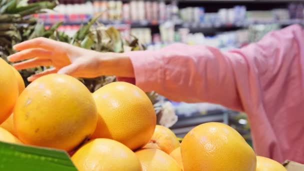 Femme dans le magasin portant le masque protecteur choisir le pamplemousse et le mettre dans le panier d'épicerie. — Video