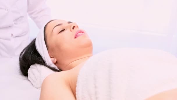 Mulher bonita com cabeça branca deitada na mesa de cosméticos pronta para procedimentos cosméticos em seu rosto. — Vídeo de Stock