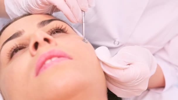 Mujer cliente sometida a procedimientos de limpieza facial, cosmetóloga en guantes médicos utilizando el instrumento especial . — Vídeos de Stock