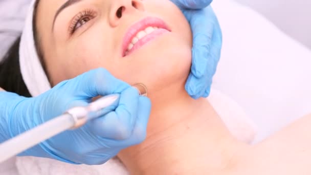 一位戴医用手套的专业女性美容师在美容外科诊所为一位年轻貌美的女性做面部皮肤水肿的面部微皮肤剥脱治疗. — 图库视频影像