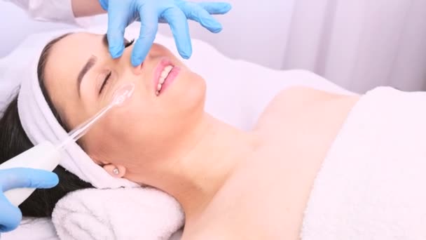 Estetista professionista in guanti medici facendo le procedure ringiovanire ad una giovane donna, leviga le rughe con strumento cosmetico, apparecchio elettrico. — Video Stock