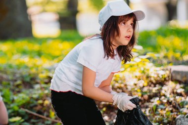 Bekar bir kız dışarıda koruyucu eldivenler ve çevre konsepti kullanarak çöp topluyor..