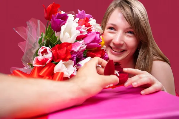 Close-up foto van een mooie vrolijke blonde dame met een tulpen gekleurd boeket en het aanvaarden van het huwelijksaanzoek van haar vriend, hij houdt een klein doosje met een ring erin. — Stockfoto