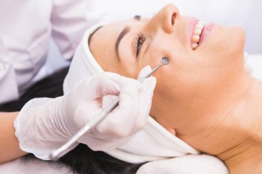 Koruyucu eldivenlerdeki kozmetik uzmanları, sivilceleri, boşalımları, yüzdeki kirlilikleri çıkarmak için tıbbi aletler kullanarak hastaların yüzüne estetik bir işlem uyguluyor..