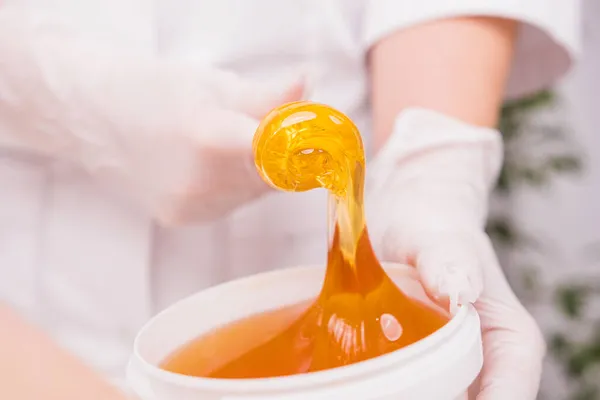 Tüy dökücü tüy temizleme prosedürü, epilasyon, epilasyon, balmumu, şekerleme konsepti için bir şeker macununun yakın fotoğrafını çek.