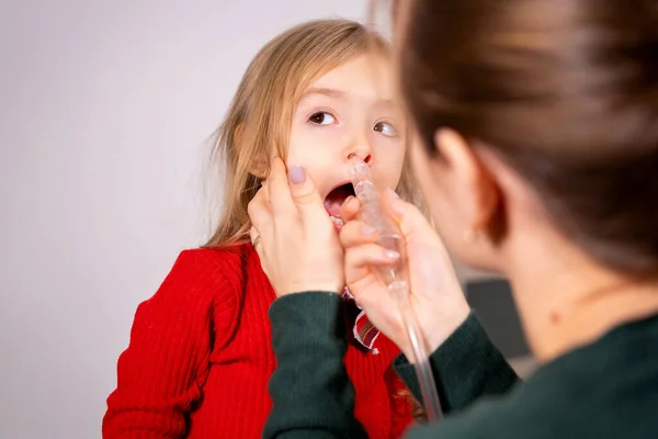 Madre enjuague su nariz niña con un aparato de inhalación para limpiar la nariz, la niña está tranquila y haciendo el procedimiento. — Foto de Stock