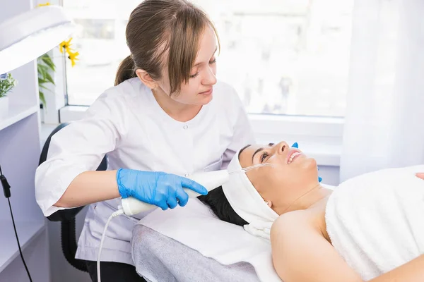Cosmetologo rende procedura microdermoabrasione sul viso contro l'acne a una donna, concetto di cosmetologia ringiovanimento. — Foto Stock