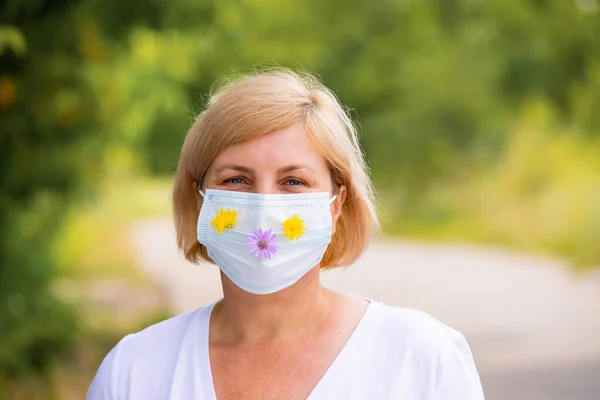 Close up photo of a blonde woman outdoors wearing the medical mask on her face to protect herself from the virus on pandemic time. — 图库照片