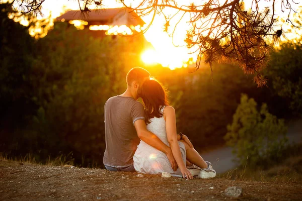 Εραστές άνδρας και κορίτσι με φόντο το ηλιοβασίλεμα, τον ήλιο ανάμεσα στα δέντρα και τον ορίζοντα. Concept ημερομηνία Ημέρα του Αγίου Βαλεντίνου, πρώτο φιλί αγάπη, για πάντα μαζί. — Φωτογραφία Αρχείου