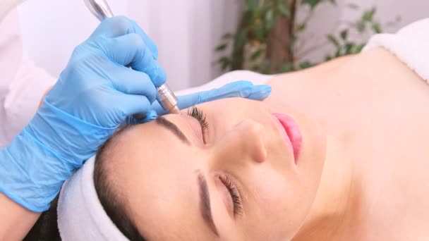 Jovem mulher recebendo levantamento massagem facial elétrica para a pele do rosto, esteticista remove rugas perto dos olhos. — Vídeo de Stock