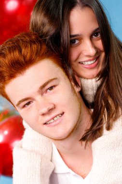 Güzel genç bir çiftin, kızıl saçlı bir oğlanın ve mavi arka planda gülümseyen esmer bir kızın fotoğrafını çek..