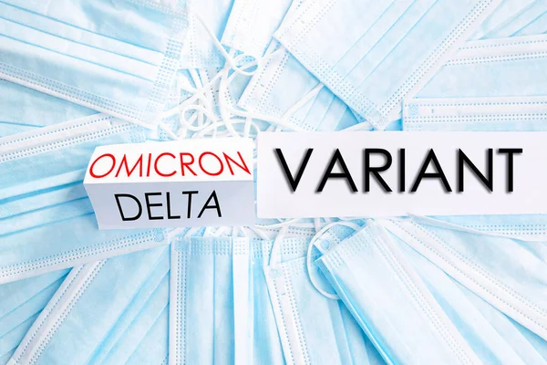 Omikron delta yeni değişken, koruma ve sağlık kavramının yazılı olduğu tıbbi maskelerle yüzleş.